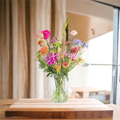 Boeket veldbloemen diverse frisse voorjaarskleuren op een heldere glazen vaas op het keukenblad in huis