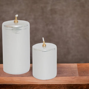 Metallic off white of zilver 7x10,5cm en 13,5cm olielamp in een cilinder vorm op een houten tafel