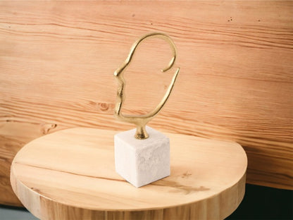Silhout van een hoofd gemaakt van metalen staaf (2,75cm) in de kleur goud h: 29cm en breedte 20cm op een houten tafel voor een houten muur