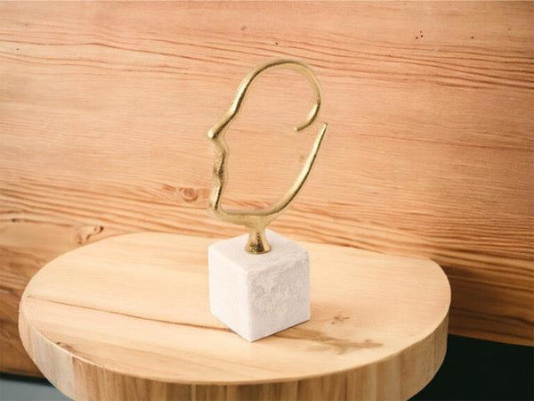 Silhout van een hoofd gemaakt van metalen staaf (2,75cm) in de kleur goud h: 29cm en breedte 20cm op een houten tafel voor een houten muur