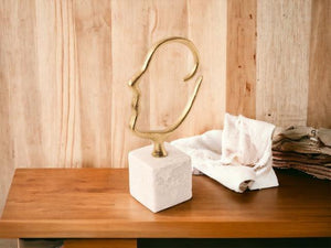 ornament van een silhouet van een hoofd gemaakt van gebogen metaalstaaf van 2,75cm dik met een breedte van 13cm en hoogte is 21cm  op een houten tafel voor een houten muur