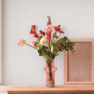 Kunstbloemen Veldboeket Paars/ Roze/ Pink inclusief Glasvaas op een houten tafel met een lichte muur met raam en fotolijstje
