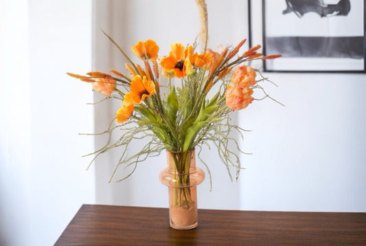 Gebonden VeldBoeket Zijden Bloemen Oranje incl. vaas op een houten tafel voor een muur