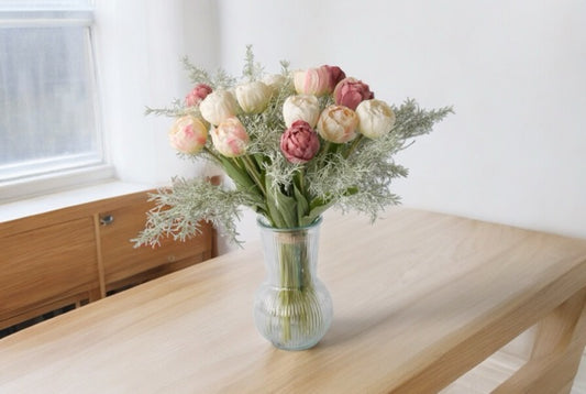 Tulpen in roze, wit en mauve in een hoge glasvaas op een houten tafel voor het raam