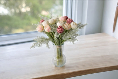 18 KUnstTulpen in roze, wit en mauve in een hoge glasvaas op een houten tafel voor het raam