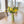 Veldboeket Zijden bloemen in de kleur Geel op een houten tafel in een groene hoogglans metalen vaas op een houten tafel voor een raam
