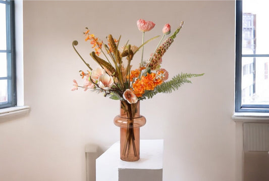 Veldboeket kunstbloemen bloemen in de kleurcombinatie Zalm en Oranje op een witte zuil voor een lichte hoek met een raam