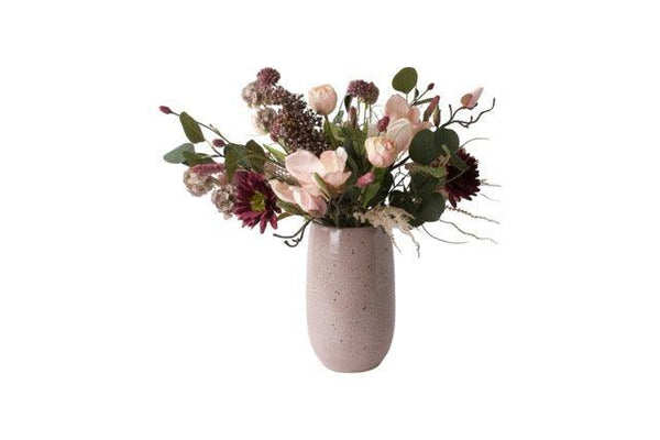 Gebonden kunstbloemen op een keramieken mauve kleurige vaas Het boeket is in een paars Roze kleurencombinatie met onder andere tulpen en gerbera en eucalyptus.