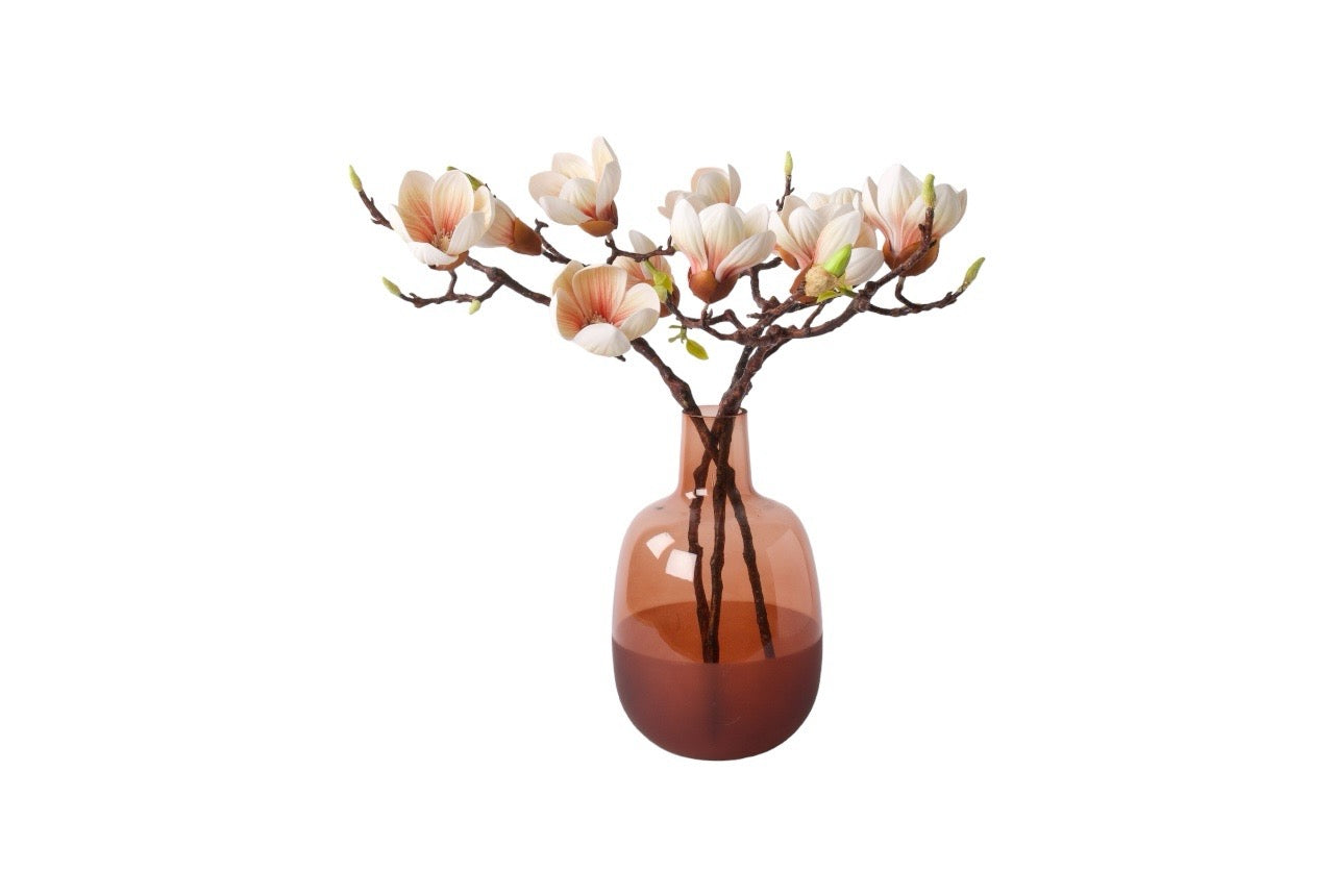 3 takken kunstbloem magnolia met diverse bloemen en knoppen in de kleur zacht roze op een cognac kleurige glasvaas