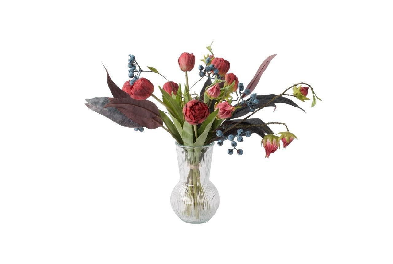 Gebonden Moederdag Boeket in Rood met Hibiscus, Tulp Rood, Bes Blauw, Tak Eucalyptus Grijs/Rood in een glasvaas van helder glas op een keukentafel voor de kastenwand