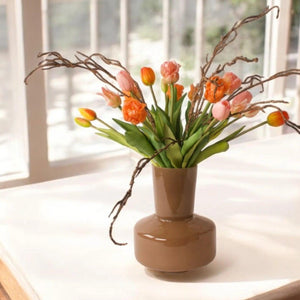 Boeket kunsttulpen in roze en oranje met twijgen op een glasvaas op tafel voor het raam - WinQ