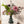 Boeket kunstbloemen in lila , grijs en paars kleuren op grote blauwe glasvaas op een tafel voor een lichte muur en houten vloer