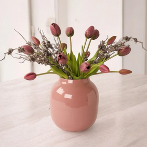 Boeket met kunsttulpen in de kleur mauve gebonden met zwarte bes op een mauve kleurige metaalvaas op een lichte tafel - WinQ