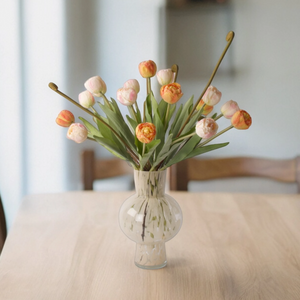 Boeket met kunsttulpen 7 oranje en 7 licht roze kunsttulpen in een glasvaas met een witte tekening in het glas  op een houten tafel  met stoelen - WinQ