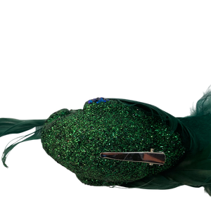 Green glittery fabric hair clip adorned with decorative feathers and blue flower accents