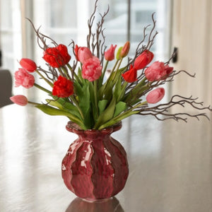 boeket parkiet kunsttulpen in rood en pink gebonden met twijgen in een rode keramieken vaas op een tafel voor het raam - WinQ