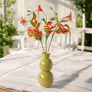 3 kunsttakken van de gloriosa in de kleur rood op een groene vaas op een houten tafel -WinQ