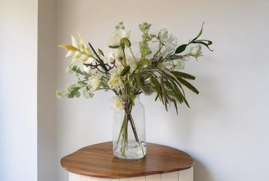 Gebonden PlukBoeket Zijden Bloemen in Wit en groen op een glasvaas op een houten tafel