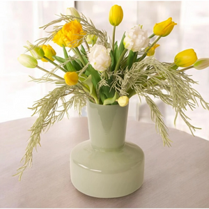 Kunsttulpen als boeket gebonden met gele  en witte parkiettulpen en tulpen op een groene glasvaas als sfeer op een tafel voor het raam- WinQ