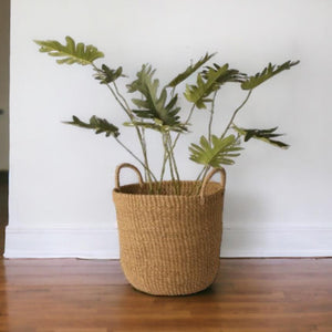 Plantenmand Abaca Handvat Naturel 33x29cm met palm op houten vloer voor een witte muur