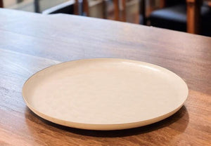decoratie schaal diameter 40cm goud aan de buitenzijde en binnenzijde een gravering in het wit op een houten tafel