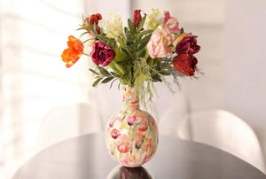 Diverse soorten tulpen in multicolor  met diverse groen gebonden op een gebloemde vaas op een tafel-WinQ