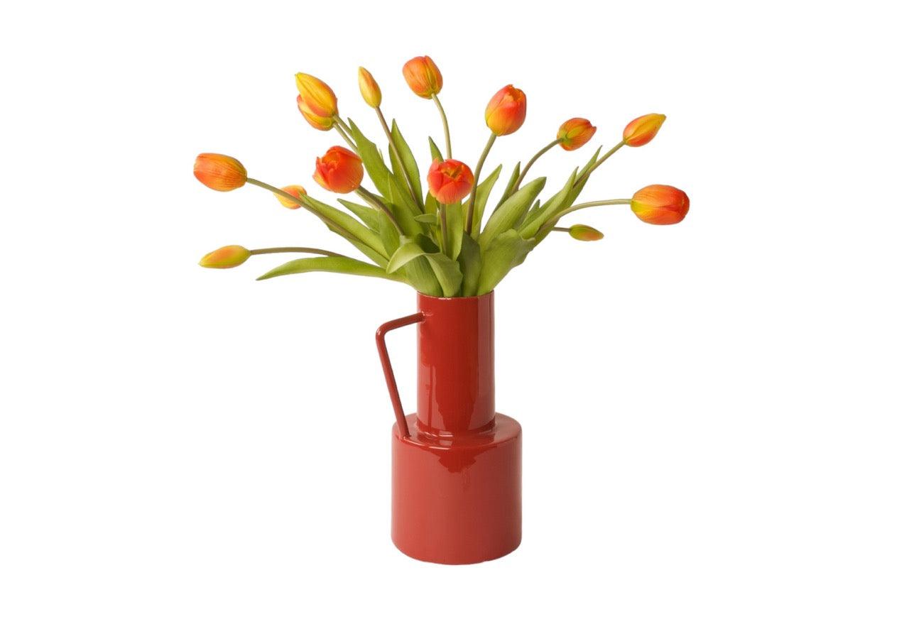 Boeket oranje kunsttulpen met groen blad op een oranje metalen vaas in model van kan