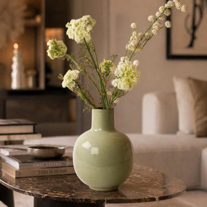 Groene metalen vaas emaille 23 x30cm hoog met witte kunstbloemen op een tafel in een luxe kamer - WinQ