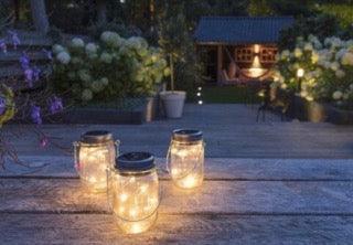 3 solar lampjes brandend in het donker op een houten tafel