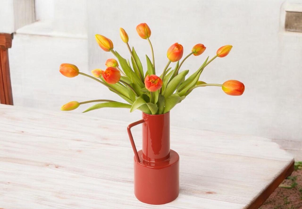 !5 oranje tulpen in verschillende groottes met groen blad op een Roo kleurige metaalvaas met handvat