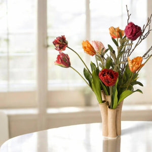 Presentatie van een tulpenvaas op een tafel met diverse kleuren tulpen in rood, oranje, paars en roze afgewerkt met twijgen -WinQ