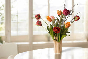 Presentatie van een tulpenvaas op een tafel met diverse kleuren tulpen in rood, oranje, paars en roze afgewerkt met twijgen -WinQ