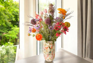 Sfeerfoto Metalen vaas Elysium in 16x31cm licht groen met bloemenprint op een tafel voor het raam - WinQ