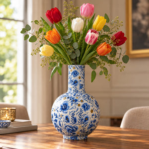 grote delfts blauwe vaas met diverse kleuren tulpen op houten tafel