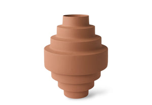 Vaas gemaakt van metaal met een geruwde betonlook structuur in een oud roze kleur met en brede diameter en trapsgewijs taps toe lopen d naar boven en beneden