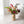 Kunstbloemenboeket met diverse kunstbloemen waaronder onder andere hibiscus en gloriosa op een metalen vaas met bloemmotief op een houten keukentafel