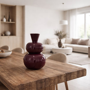 Bordeauxrode design vaas op houten eettafel in modern, licht interieur