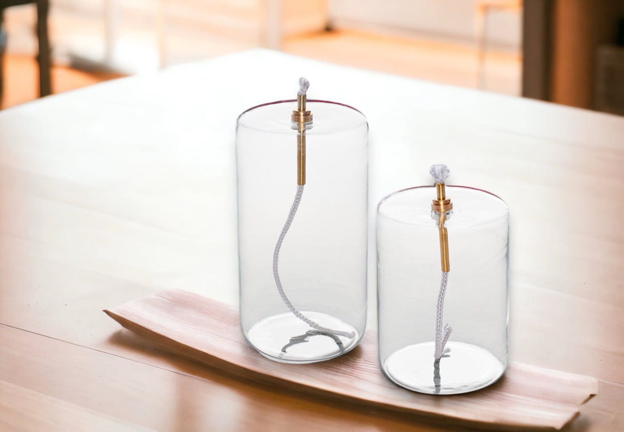 olielampen van helder glas in cilinder vorm diameter 7cm en hoogte 10cm en 13,5cm op een houten tafel