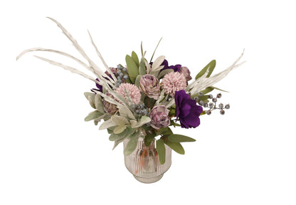kort gebonden boeket met kunstbloemen op een glasvaas . met dahlia in paars en lila en groen accenten  van voren gefotografeerd