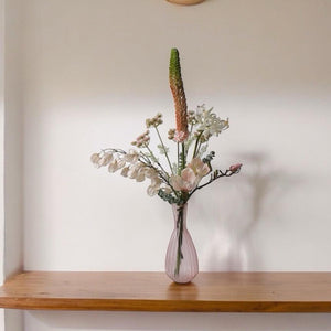 Plukboeket van Kunstbloemen zacht Roze.Physalis wit Magnolia zacht roze Eremures zacht roze Nerine wit Fluitekruid Roze Eucalyptus frosted op een houttafel voor een lichte muur