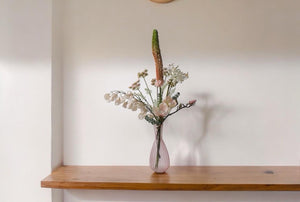 Plukboeket van Kunstbloemen zacht Roze.Physalis wit Magnolia zacht roze Eremures zacht roze Nerine wit Fluitekruid Roze Eucalyptus frosted op een houttafel voor een lichte muur