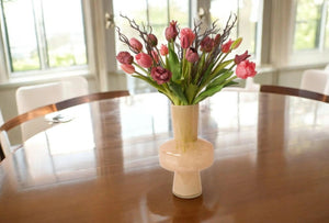 boeket van tulpen en parkiettulpen in de kleuren mauve en Fuchsia gebonden met twijgen in een beige kleurige glasvaas op een gladde houten tafel - WinQ