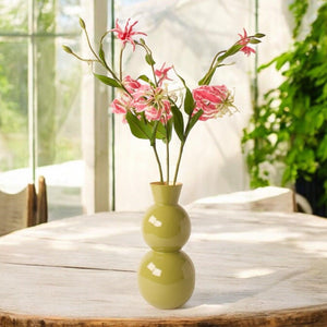 3 takken van de gloriosa op een groene vaas op een houten tuintafel -  WinQ