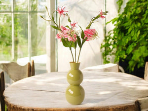 3 takken van de gloriosa op een groene vaas op een houten tuintafel -  WinQ