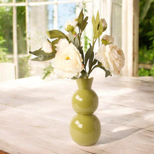 Sfeerfoto van een vaas met 3 takken kunst pioenrozen met meerder bloemen in de kleur wit gefotografeerd in een serre op een houten tafel- WInQ