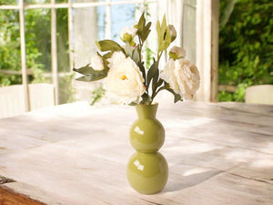 Sfeerfoto van een vaas met 3 takken kunst pioenrozen met meerder bloemen in de kleur wit gefotografeerd in een serre op een houten tafel- WInQ