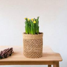 Plantenmand Abaca Naturel 24x31cm met narcissen op een houten tafel;