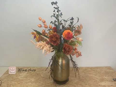 video van boeket met bloemen in de kleuren terra oranje en crème op een gouden vaas