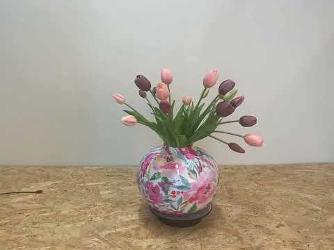 video van kunsttulpen in de kleur mauve en rosé op een bolvormige vaas met een bloemenprint