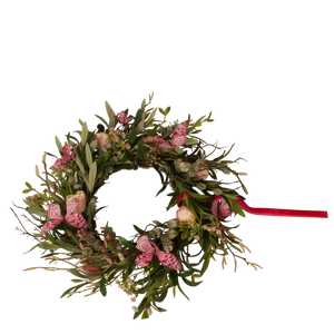 Kunstbloemen voorjaarskrans met roze bloemen, groene bladeren en rode lint voor interieurdecoratie